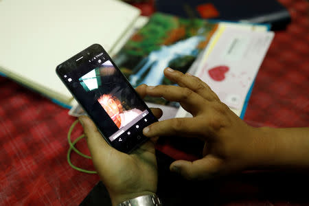 Chen Hong-zhi, 26, who suffers from short-term memory loss, looks at a photograph of himself on his mobile phone in Hsinchu, Taiwan, July 2, 2018. REUTERS/Tyrone Siu