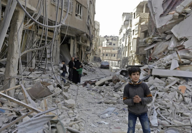 Syrians walk in a destroyed street in the Eastern Ghouta town of Saqba on March 18, 2018 as civilians return to the area after regime forces took control of the southern pocket held by the Faylaq al-Rahman rebel group