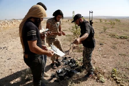 Rebel fighters from the Ahrar al-Sham Movement inspect a site as they gather pieces of the wreckage of an unidentified and unmanned aircraft that had crashed at their base in Maarchmarein village in the southern part of Idlib province, Syria October 20, 2015. REUTERS/Khalil Ashawi