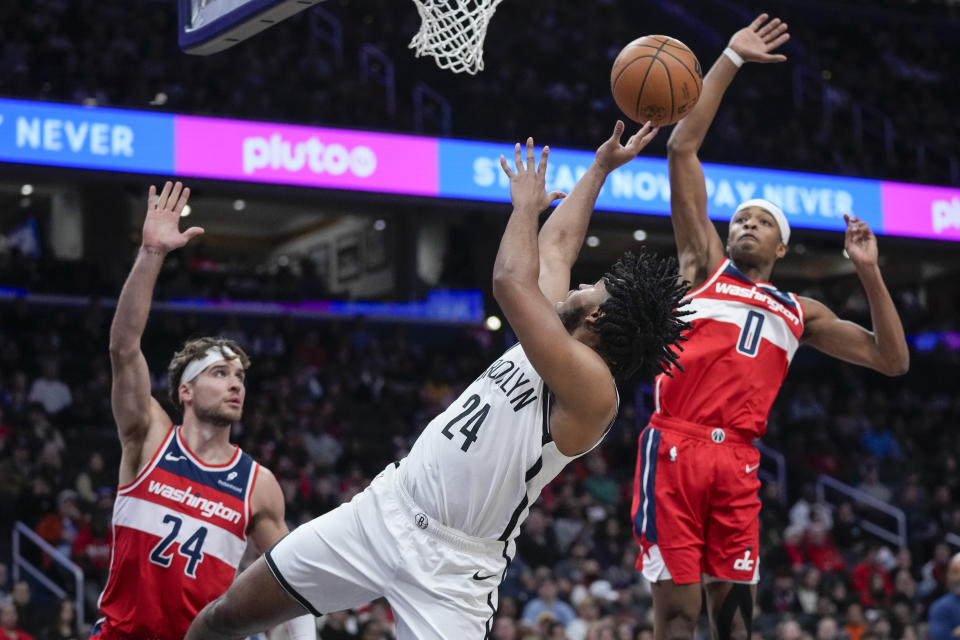 Brooklyn Nets guard Cam Thomas (24) shoots between Washington Wizards forward Corey Kispert (24) and guard Bilal Coulibaly (0) during the first half of an NBA basketball game Friday, Dec. 29, 2023, in Washington. (AP Photo/Alex Brandon)