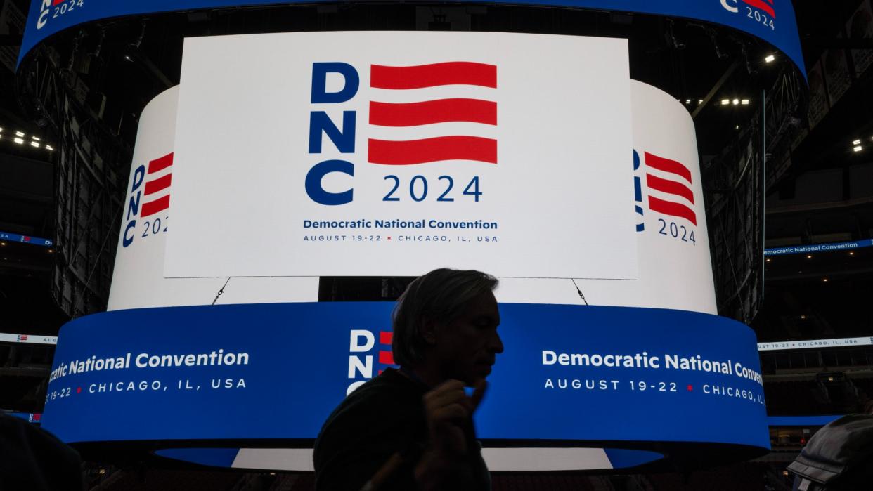  A man walks past the United Center scoreboard displaying the logo for the 2024 Democratic National Convention. 