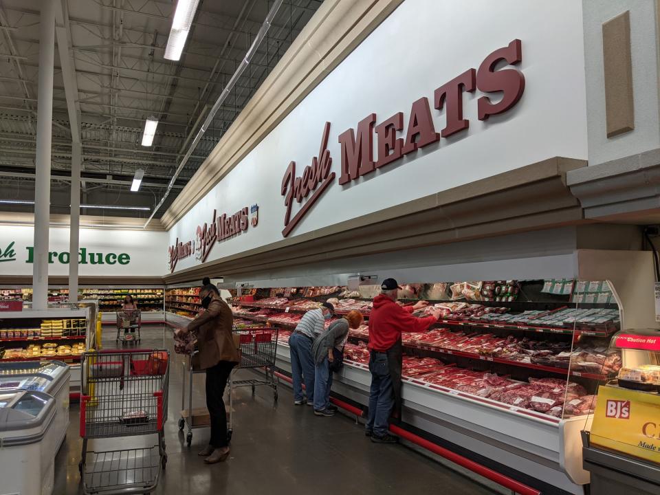 "Meats" sign and customers picking packages of meat