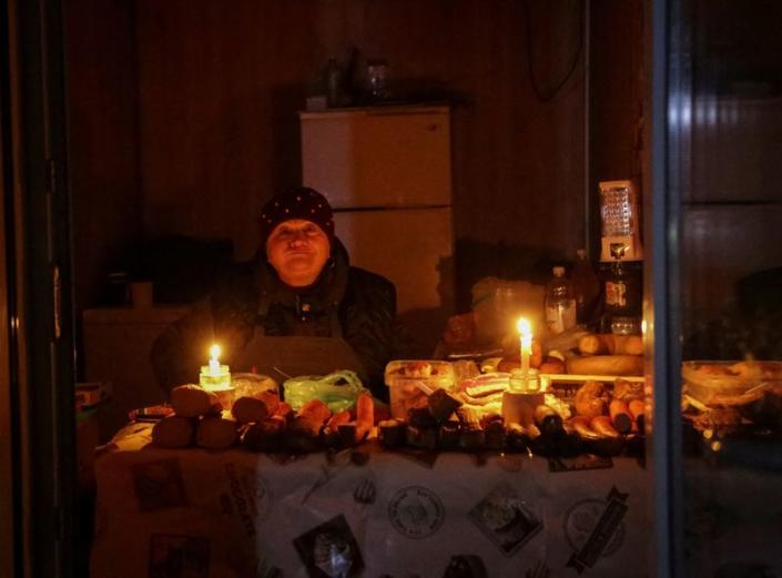 FILE PHOTO: A vendor waits for customers in a small store, lit with candles during a power outage, after critical civil infrastructure was hit by Russian missile attacks in Odesa