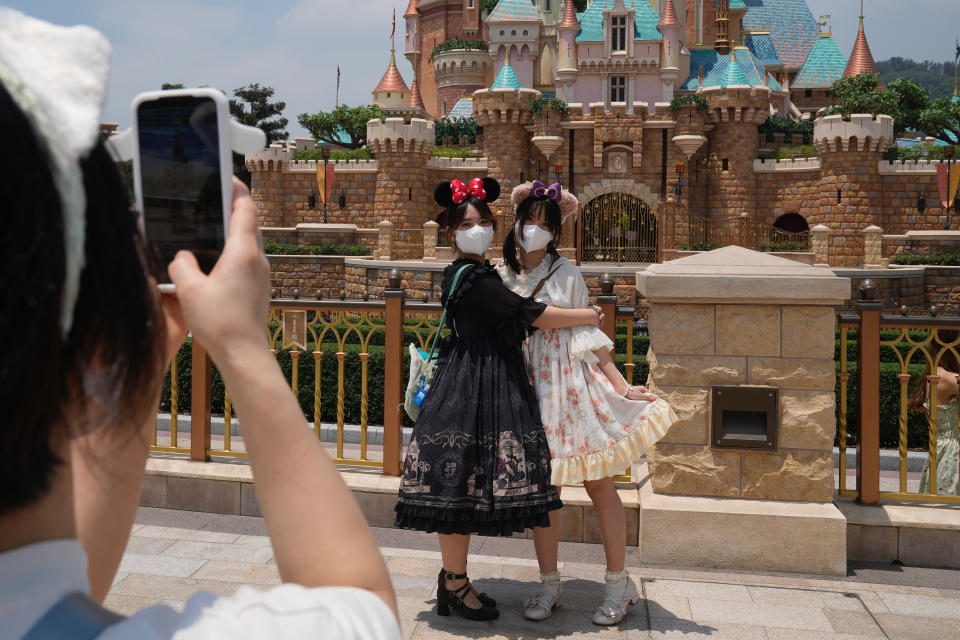 Visitors wearing face masks take photos at the Hong Kong Disneyland, Thursday, April 21, 2022. Hong Kong Disneyland reopened to the public after shutting down due to a surge in COVID-19 infections. (AP Photo/Kin Cheung)