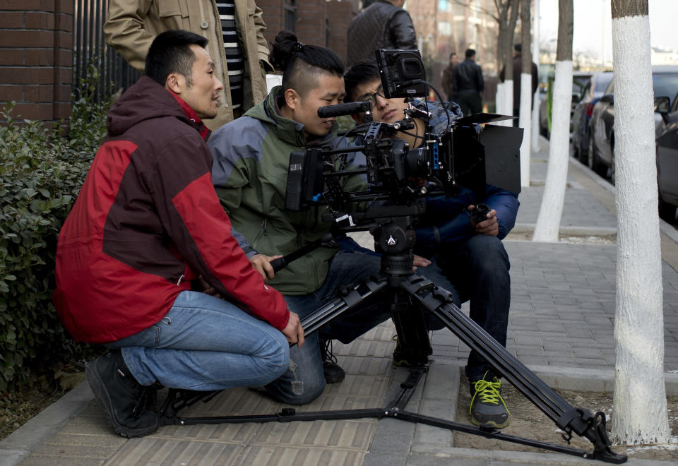 In this Dec. 4, 2013 photo, Chinese director Sun Zhendong, left, and his crew prepare to film the “Mr. Ball” microfilm near a residential buildings in Changping, on the outskirts of Beijing. Microfilms, uploaded to Chinese YouTube-style and video-streaming sites, offer themes and subjects you won’t come across in China’s strictly censored cinemas. And thanks to video-capturing smartphones and basic editing software available on laptops, anyone can be a director these days. (AP Photo/Andy Wong)