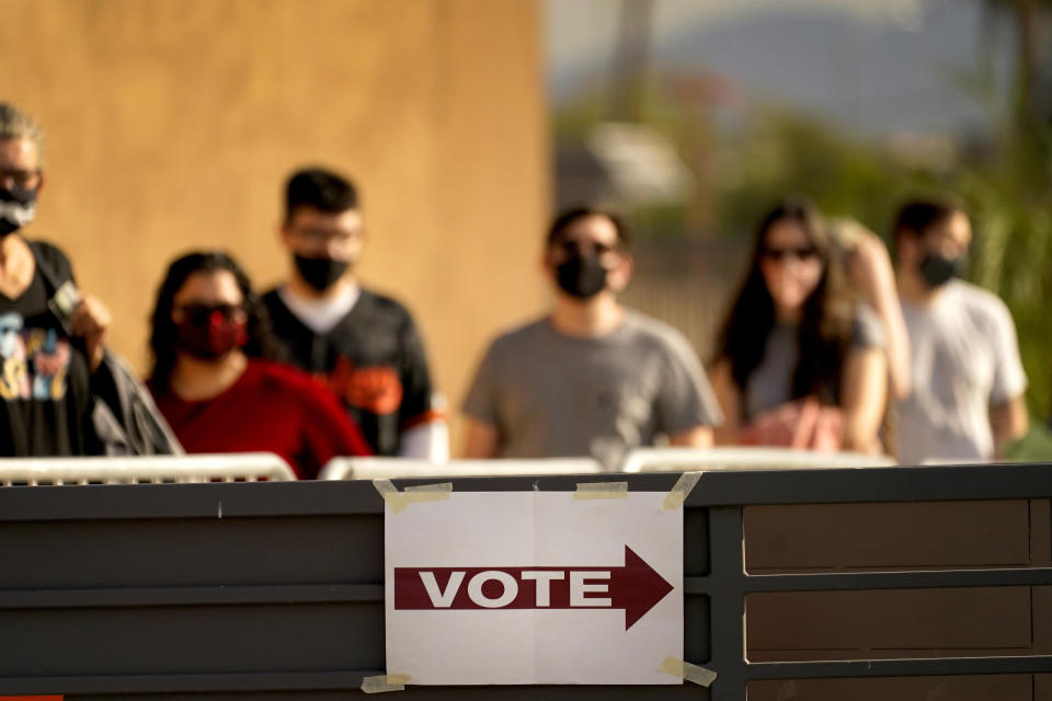 FILE - In this Tuesday, Nov. 3, 2020, file photo, voters stand in line outside a polling station, on Election Day in Mesa, Ariz. Ron Watkins, a prolific promoter of false conspiracies about the 2020 election who is closely tied to the QAnon movement, says he's running for Congress as a Republican in Arizona. (AP Photo/Matt York, File)