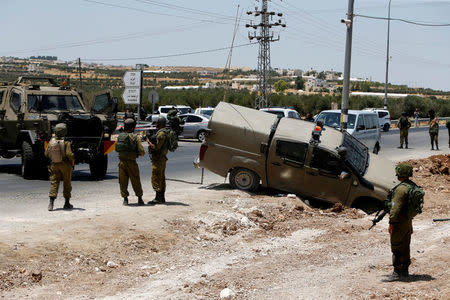 Israeli soldiers stand guard at the scene of a car ramming and stabbing attack at Tekoa checkpoint near the West Bank city of Bethlehem July 10, 2017. REUTERS/Mussa Qawasma