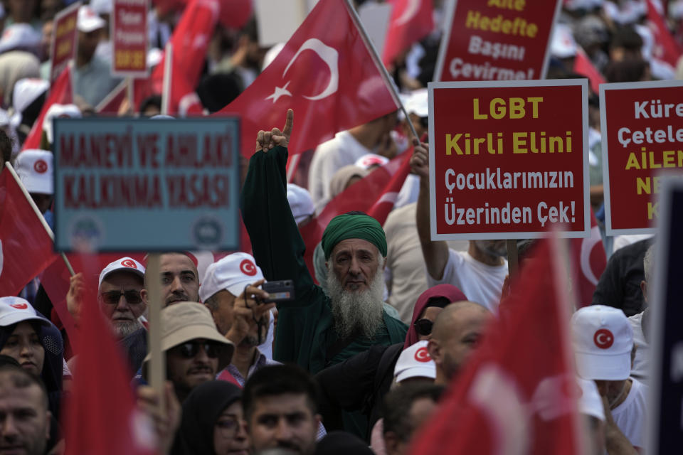FILE - Demonstrators hold banners that read, "Law for the development of the spirit and moral" and "LGBTQ, remove your dirty hand from our children" during an anti LGBTQ protest in Fatih district of Istanbul, Sunday, Sept. 18, 2022. (AP Photo/Khalil Hamra, File)