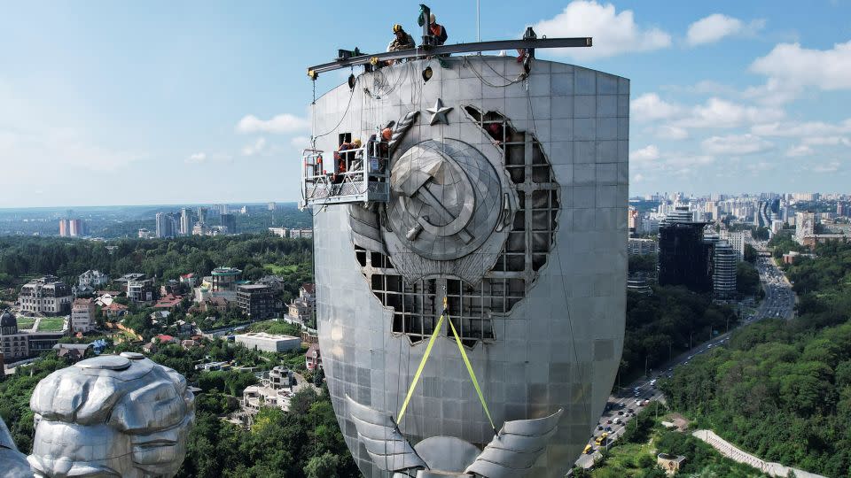 Workers remove the Soviet-era emblem from the motherland monument in Kyiv on August 1, 2023.  - Valentyn Ogirenko/Reuters