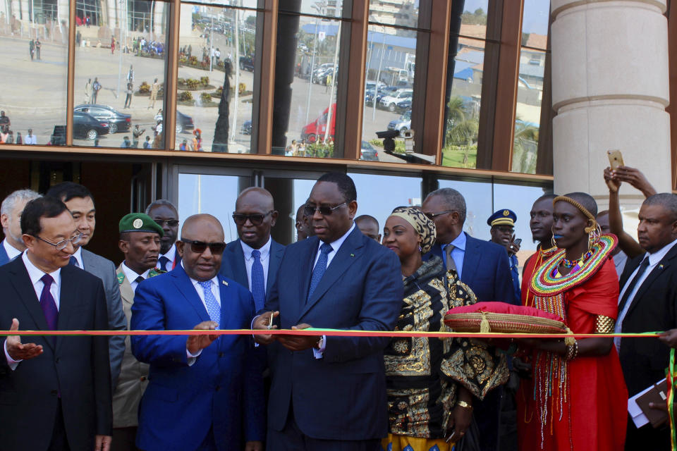 In this photo taken Thursday, Dec. 6, 2018, Senegalese president Macky Sall, center, cuts a ribbon in the colors of the Senegalese flag, surrounded by foreign dignitaries in Dakar, Senegal. The new museum in Dakar is the latest sign that welcoming spaces across the continent are being prepared. Focusing on Africa and its diaspora, it has been decades in the making. (AP Photo/Amelia Nierenberg)