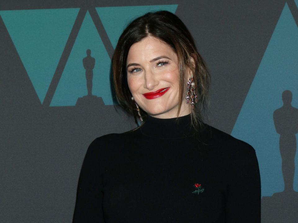 Kathryn Hahn in a black turtleneck, a blue tiered skirt, and a red lip