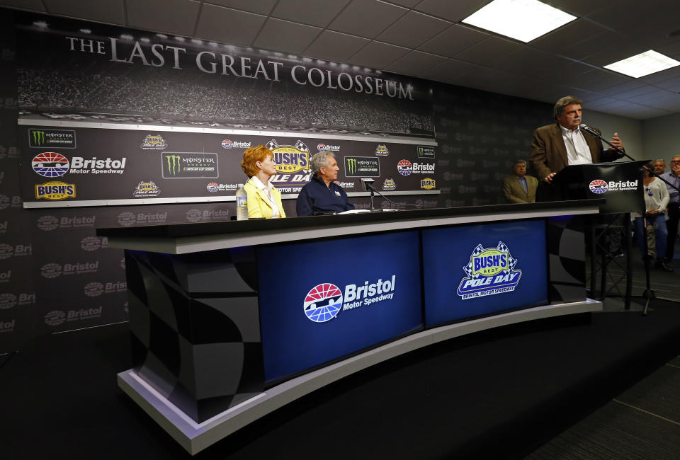 THIS CORRECTS THAT MIKE HELTON IS VICE-CHAIRMAN, NOT VICE-PRESIDENT - Hall of Fame driver and FOX television announcer Darrell Waltrip, center, and his wife, Stevie, listen as Mike Helton, NASCAR vice-chairman, speaks to media during a press conference announcing Waltrip's retirement from the booth before practice for a NASCAR Cup Series auto race, Friday, April 5, 2019, in Bristol, Tenn. (AP Photo/Wade Payne)