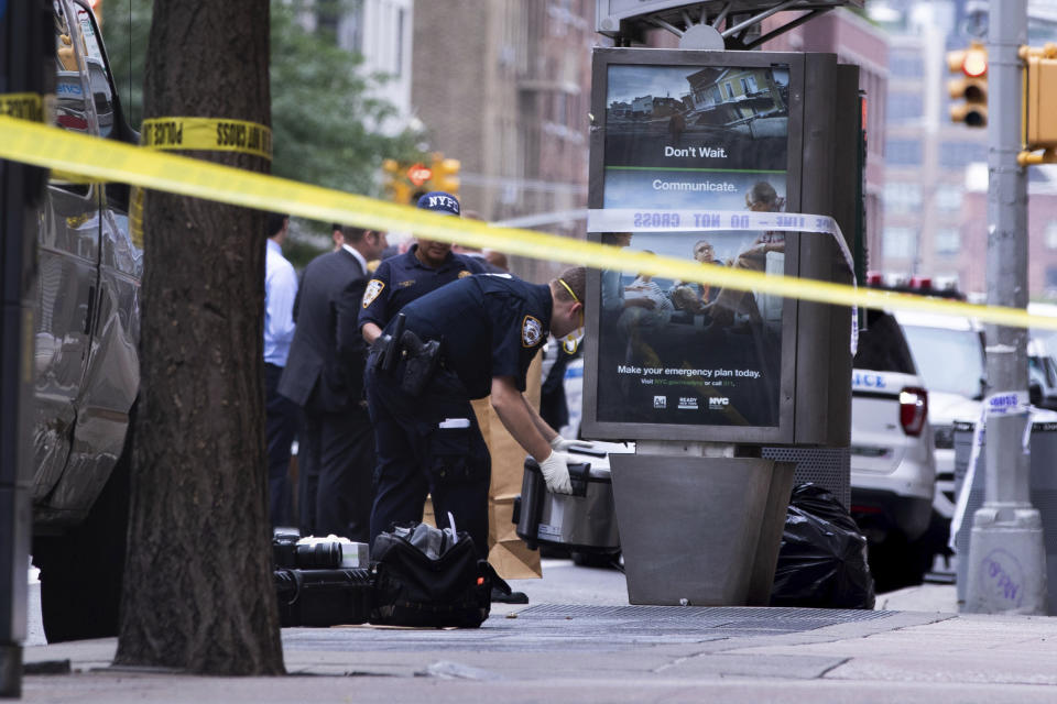 An investigator picks up a suspicious package that was thought to be an explosive device in Manhattan's Chelsea neighborhood Friday, Aug. 16, 2019, in New York. The appliance was deemed harmless and taken away as evidence. (AP Photo/Kevin Hagen).