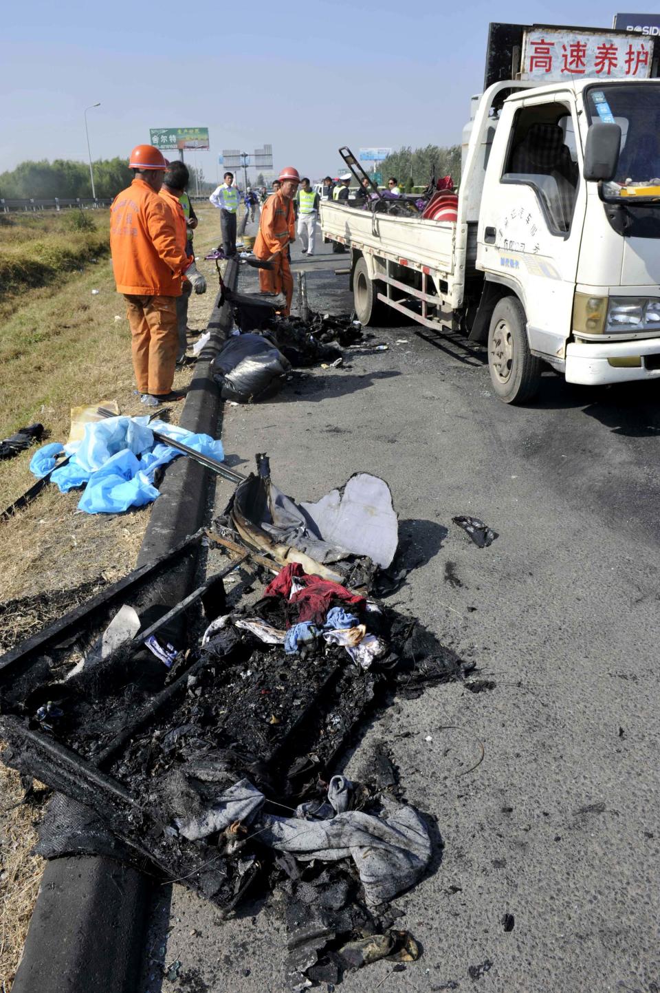 In this photo released by China's Xinhua News Agency, rescue workers clean up debris after an accident on an expressway near Tianjin, China, Monday, Oct. 1, 2012. Five Germans and a Chinese citizen were killed when their bus burst into flames after hitting the back of a truck Monday, Xinhua said. (AP Photo/Xinhua, Yue Yuewei) NO SALES