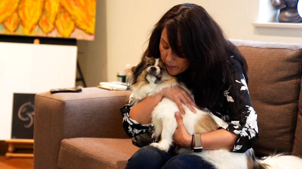 Simone Lee sits on a couch and holds Tibetan spaniel Dexter on her lap.