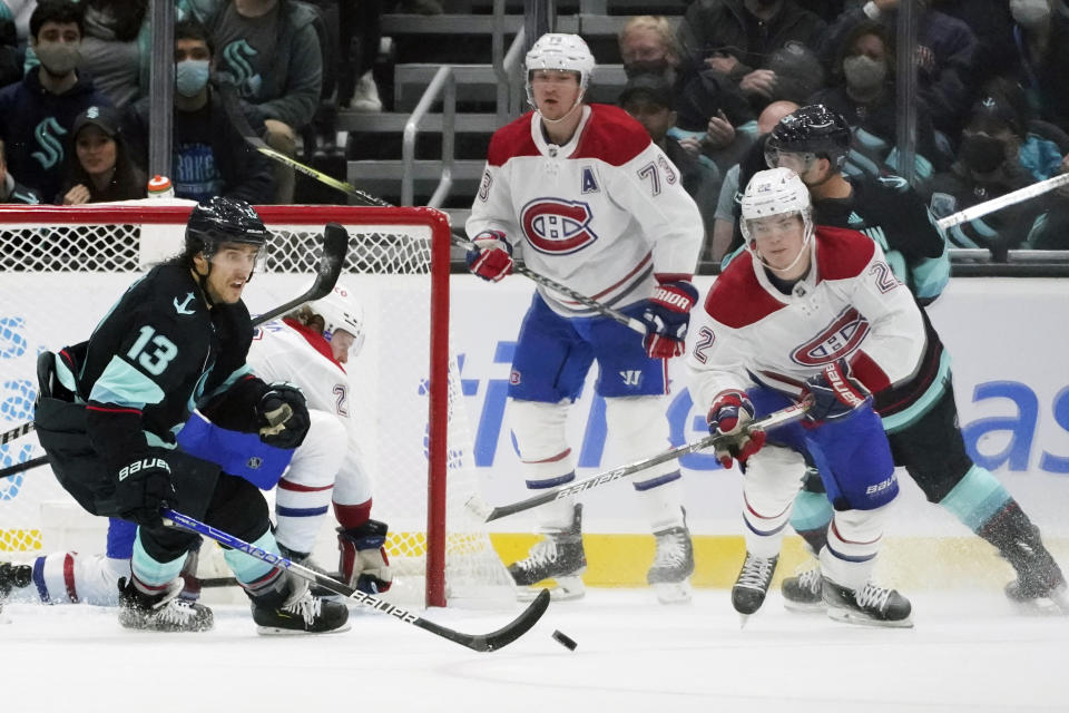 Seattle Kraken left wing Brandon Tanev (13) and Montreal Canadiens right wing Cole Caufield (22) eye the puck during the third period of an NHL hockey game, Tuesday, Oct. 26, 2021, in Seattle. The Kraken won 5-1. (AP Photo/Ted S. Warren)