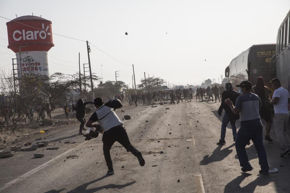 Drivers throw rockers trying to break a blockade on the Pan-American South Highway set up by farmworkers, on the fourth day of protests against the Agricultural Promotion Law, in Villacuri, Ica province, Peru, Thursday, Dec. 3, 2020. The farmworkers are asking for the elimination of the law, demanding better wages and health benefits. (AP Photo/Rodrigo Abd)