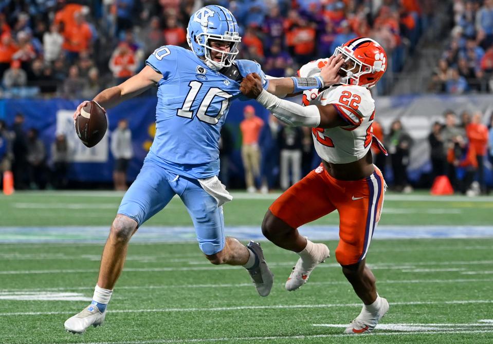 North Carolina Tar Heels quarterback Drake Maye (10) stiff arms Clemson Tigers linebacker Trenton Simpson (22) during the second quarter of the ACC Championship game at Bank of America Stadium.