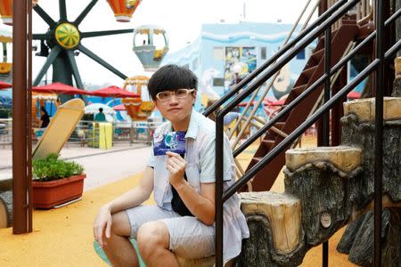 JoJo Wong, who was born six months before the Hong Kong's handover to Chinese rule in 1997, poses with his childhood photo which was taken around the same spot in 1999, at Ocean Park in Hong Kong, China June 14, 2017. REUTERS/Tyrone Siu