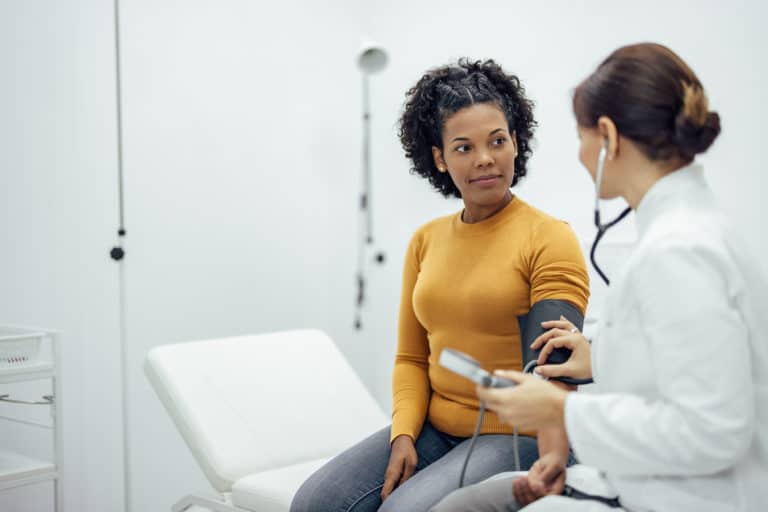 A doctor takes a patient's blood pressure in a clinical office.