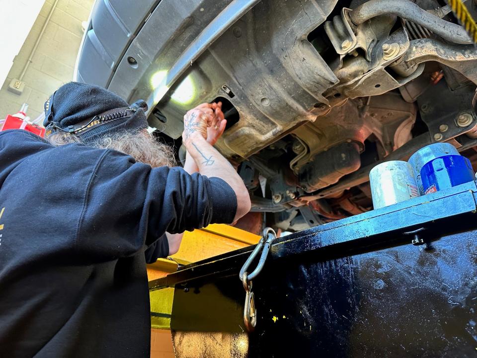 Oil changer Eric Moore drains the oil from a customer's vehicle at the new Costa Oil Chapman Highway location on Nov. 16, 2023.