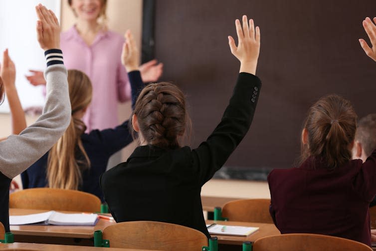 Teenagers raising hands in class