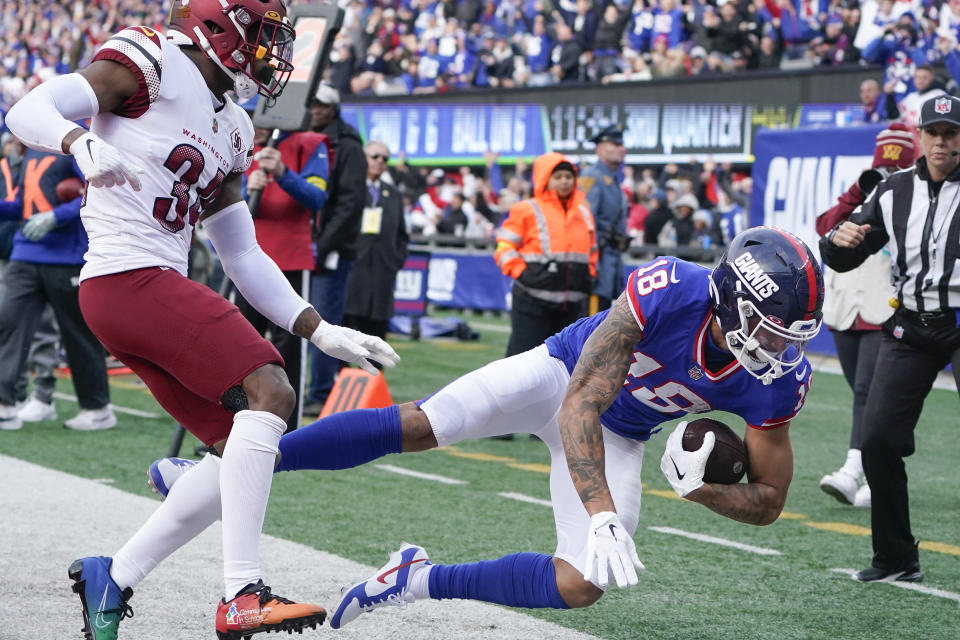 New York Giants' Isaiah Hodgins, right, is pushed out of bounds by Washington Commanders' Christian Holmes after scoring a touchdown during the second half of an NFL football game, Sunday, Dec. 4, 2022, in East Rutherford, N.J. (AP Photo/John Minchillo)