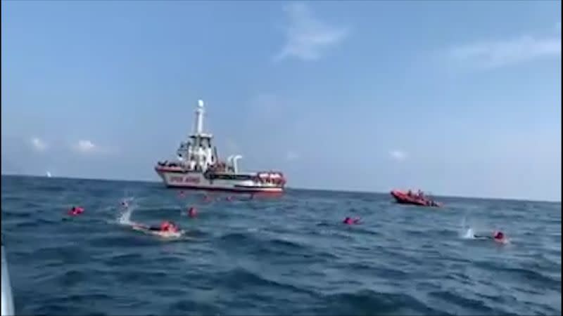 Migrants swim away from Spanish rescue ship Open Arms after more than 70 of them jumped from the ship to attempt to reach the coast, at sea near Palermo