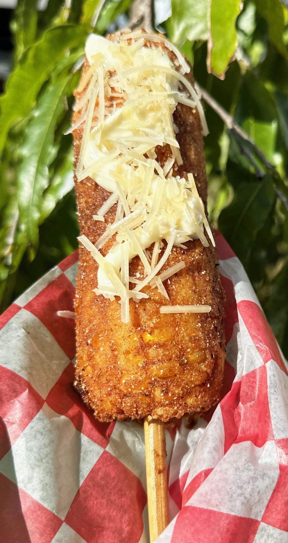 Deep-fried corn on a stick, a seasoned ear of corn dipped in buttermilk and egg mixture, rolled in flour corn meal, deep fried and topped with mayonnaise and parmesan, is available at Cantina Louie's by Meatball Factory at the 2023 Indiana State Fair.
