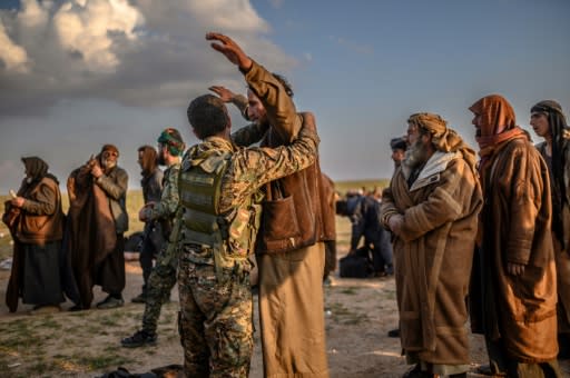 Men suspected of being Islamic State group fighters are searched after leaving the jihadists' last holdout of Baghouz in Syria