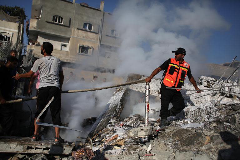 A firefighter drags a hose to the site of a destroyed house in Rafah in the south of the Gaza Strip on August 20, 2014, targeted late the night before in an Israeli airstrike