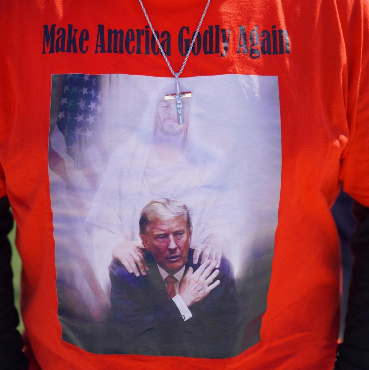 A man wears a T-shirt that says: 'Make American Godly' and shows Jesus Christ placing his hands on Donald Trump's shoulders