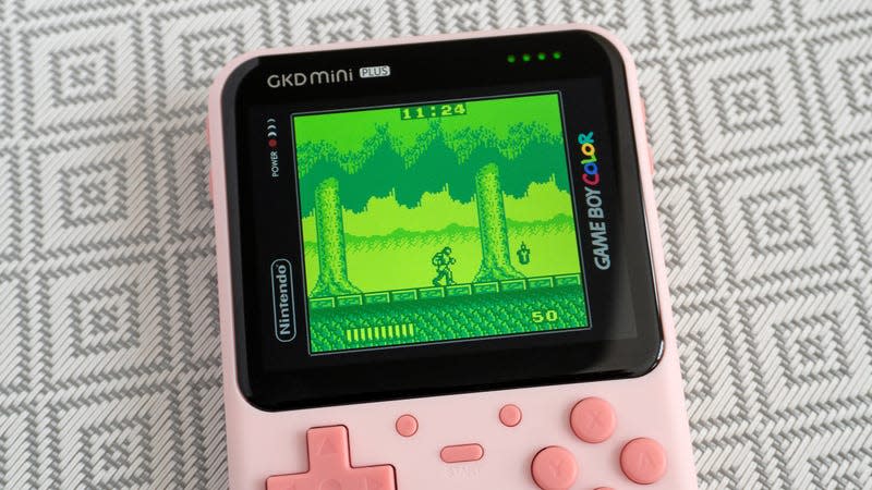 A close-up of the GKD Mini Plus handheld's screen showing a Game Boy game being played with a themed screen overlay.