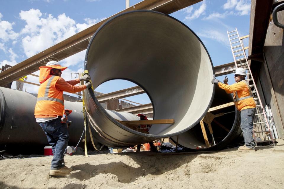 Crews lower a section of pipe.