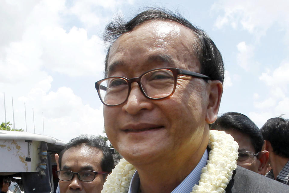 FILE - In this Aug. 16, 2015, file photo, Sam Rainsy, leader of the opposition Cambodia National Rescue Party, greets his party supporters upon his arrival at Phnom Penh International Airport in Phnom Penh, Cambodia. Phnom Penh Municipal Court has convicted and sentenced the exiled leader and senior members of the country's banned opposition party to more than 20 years in prison, effectively barring them from ever returning home. The decision taken by the court late Monday, March 1, 2021 was condemned by the head of the Cambodia National Rescue Party , or CNRP, human rights organizations and the United States embassy. The trial was held in absentia as all the party leaders are living abroad. (AP Photo/Heng Sinith, File)