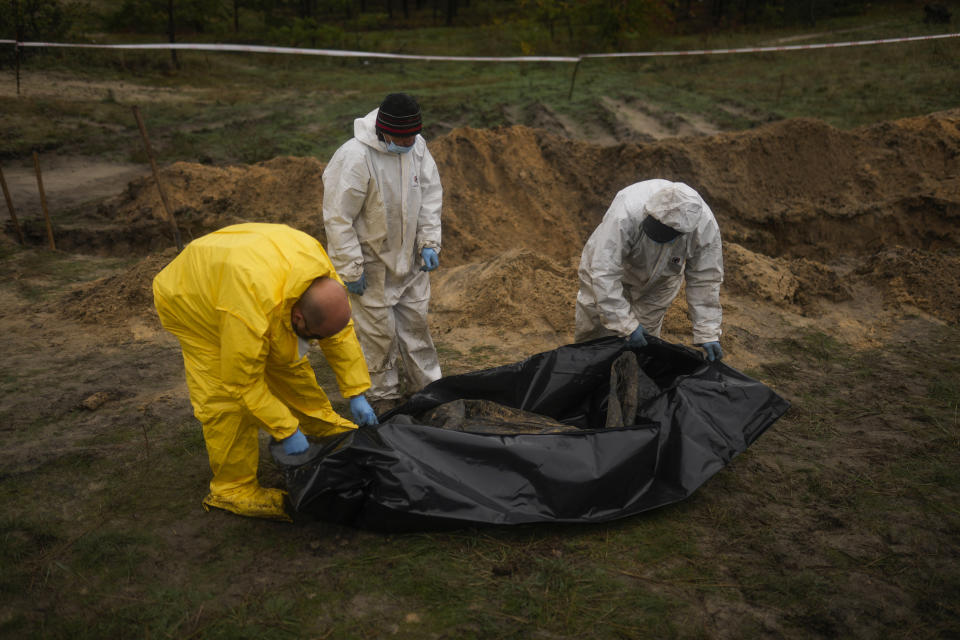 Members of a forensic team work at an exhumation in a mass grave in Lyman, Ukraine, Tuesday, Oct. 11, 2022. (AP Photo/Francisco Seco)