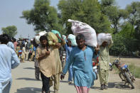 Displaced families receive food aid as they take refuge in an open area, after fleeing their flood-hit homes, in Multan, Pakistan, Wednesday, Aug. 31, 2022. Officials in Pakistan raised concerns Wednesday over the spread of waterborne diseases among thousands of flood victims as flood waters from powerful monsoon rains began to recede in many parts of the country. (AP Photo/Shazia Bhatti)