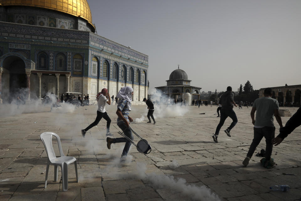 FILE - Palestinians run away from tear gas during clashes with Israeli security forces at the Al Aqsa Mosque compound in Jerusalem's Old City Monday, May 10, 2021. (AP Photo/Mahmoud Illean, File)