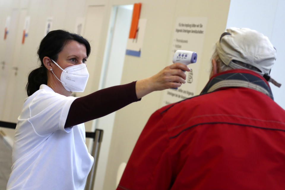 Medical staff takes the temperature of an elderly man arriving at a local vaccination centre as the spread of the coronavirus disease (COVID-19) continues in Ebersberg near Munich, Germany, Monday, March 22, 2021. (AP Photo/Matthias Schrader)