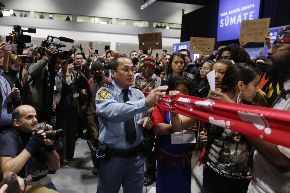 U.N. security staff gab banners during a protest to draw attention to lack of action by some countries to find real solutions to the climate problems, at the COP25 climate talks congress in Madrid, Spain, Wednesday, Dec. 11, 2019. (AP Photo/Paul White)