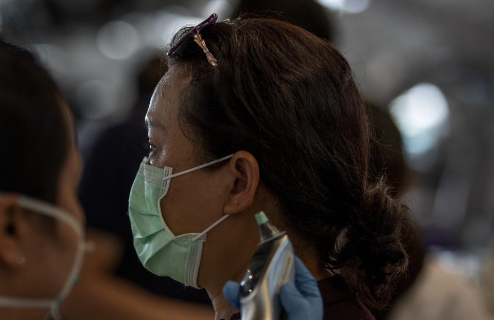 A health worker checks the temperature of tourist from Wuhan, China, as she waits for a charter flight back to Wuhan at the Suvarnabhumi airport, Bangkok, Thailand, Friday, Jan. 31, 2020. A group of Chinese tourists who have been trapped in Thailand since Wuhan was locked down due to an outbreak of new virus returned to China on Friday. (AP Photo/Gemunu Amarasinghe)