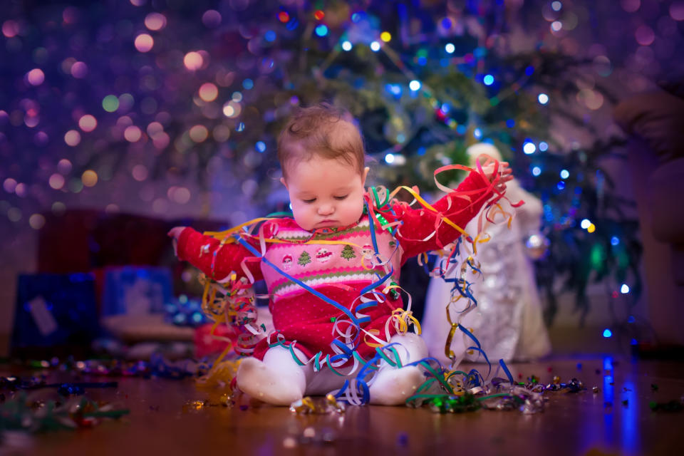 Cute funny baby girl sitting under Christmas tree