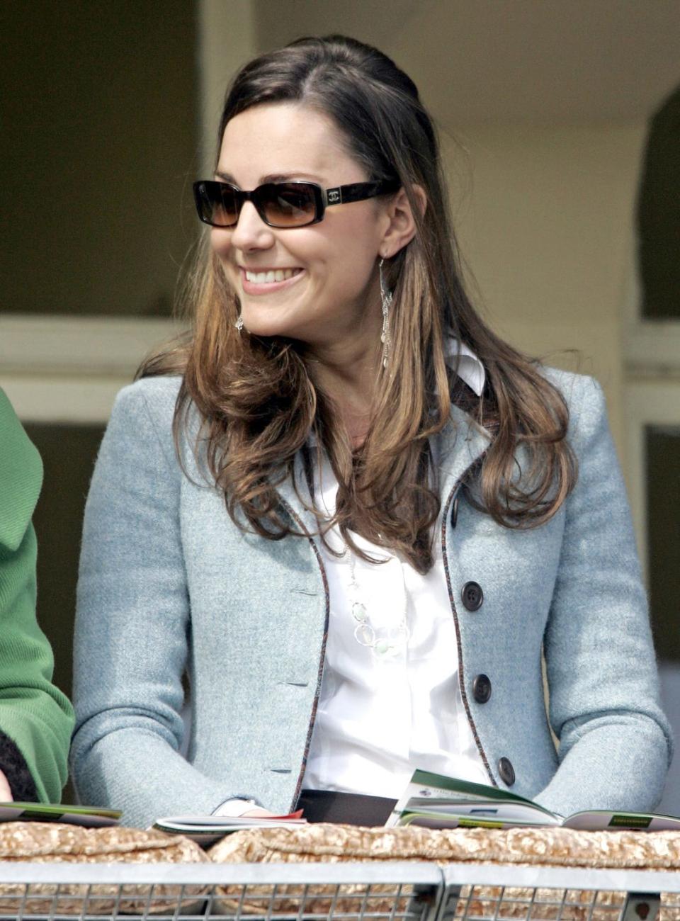 <p>Smiling at the Cheltenham Festival Race Meeting in sunglasses and a pale blue blazer.</p>