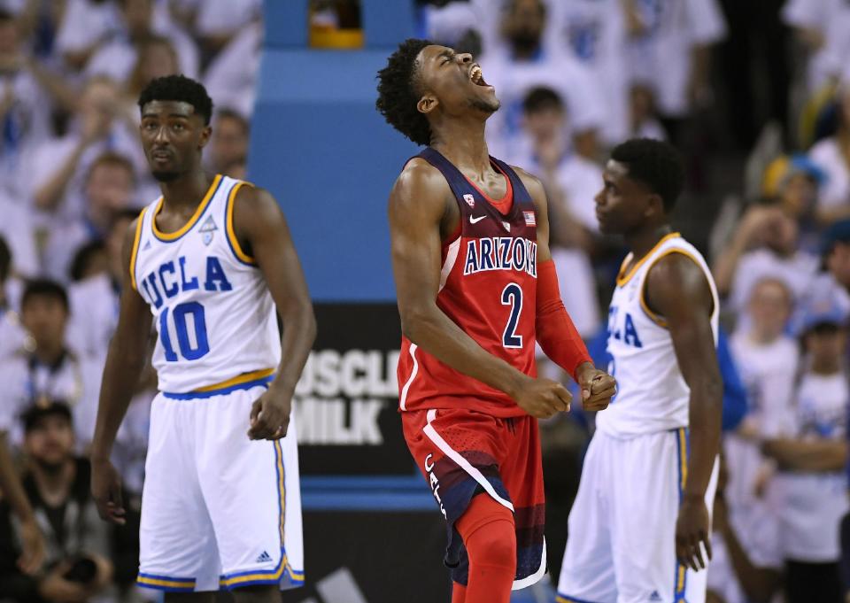 Arizona guard Kobi Simmons, center, celebrates after scoring as UCLA guard Isaac Hamilton, left, and guard Aaron Holiday stand in the background during the second half of an NCAA college basketball game, Saturday, Jan. 21, 2017, in Los Angeles. Arizona won 96-85. (AP Photo/Mark J. Terrill)