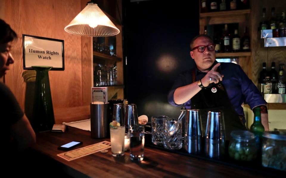 Coup co-founder Sother Teague explains to a customer how the bar's profit distribution system works, Tuesday, April 25, 2017, in New York - AP