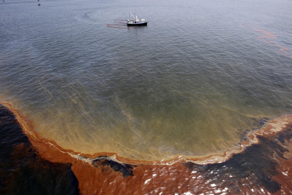 FILE - This Wednesday, May 5, 2010 file picture shows a plume of oil as a shrimp boat uses booms to collect oil in the waters of Chandeleur Sound, La. On April 20, 2010, a well blew wild under a BP oil platform in the Gulf of Mexico. Eleven workers were missing that day, and would later be declared dead. Ten years after the explosion on that Deepwater Horizon rig off Louisiana's coast, The Associated Press is making the original story and photographs available. (AP Photo/Eric Gay)