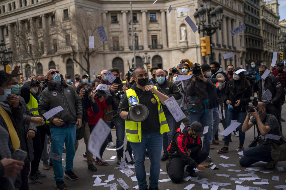 Taxi drivers throw fake money in the air during a protest in Barcelona downtown, Spain, Thursday, March 18, 2021. Hundreds of yellow-and-black cabs disrupted Barcelona's road traffic on Thursday to protest against the return of the ride-hailing giant Uber to the northeastern city after a 2-year hiatus. (AP Photo/Emilio Morenatti)