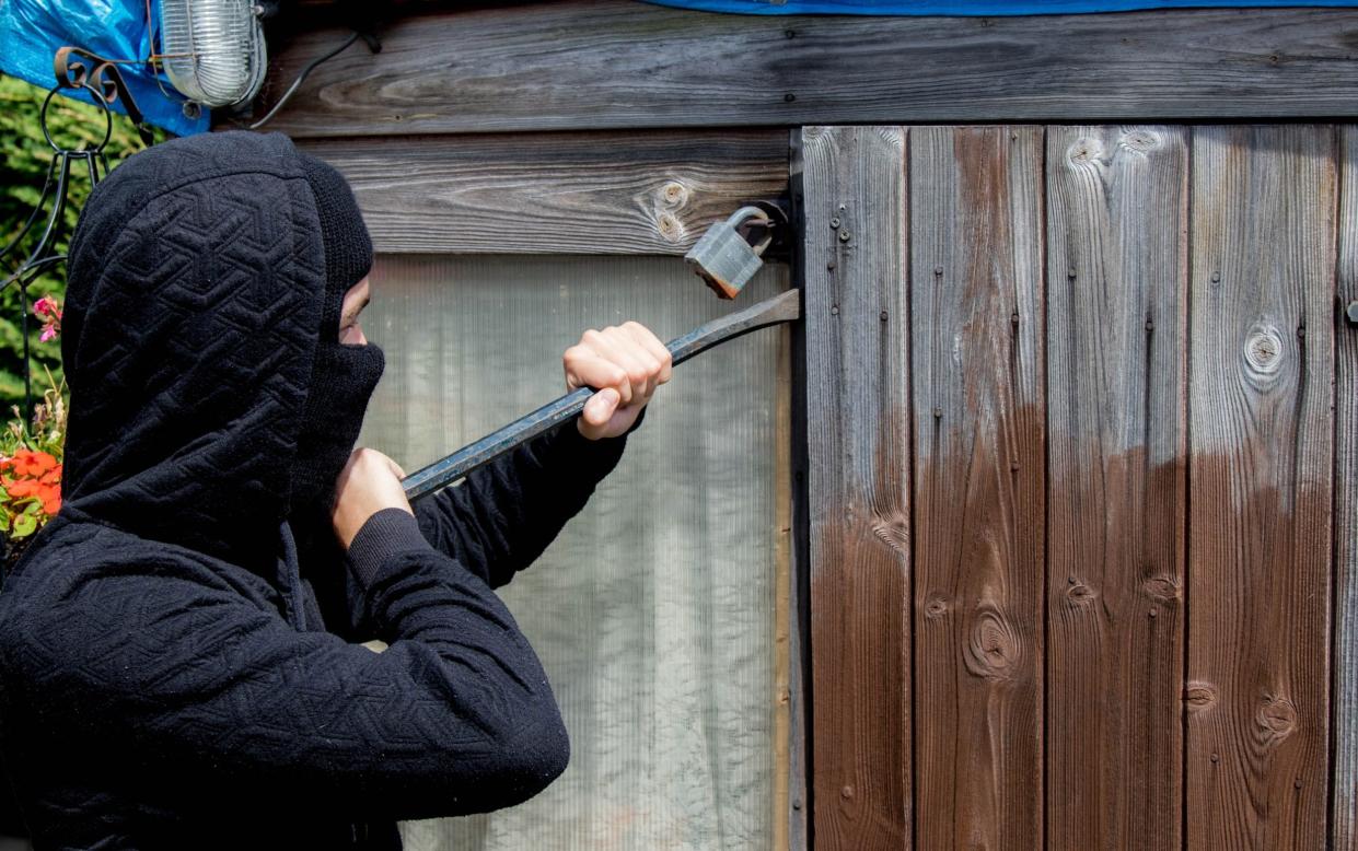 A burglar attempts to break into a shed - Ben Gingell/iStockphoto