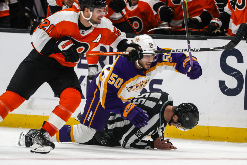 Los Angeles Kings defenseman Sean Durzi, center, crashes with referee Kyle Flemington, right, during the third period of an NHL hockey game against the Philadelphia Flyers Saturday, Dec. 31, 2022, in Los Angeles. The Philadelphia Flyers won 4-2. (AP Photo/Ringo H.W. Chiu)