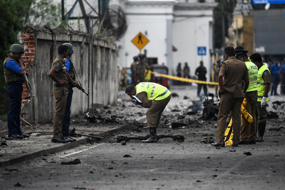 Sri Lankan security personnel inspect the debris of a car after it explodes when police tried to defuse a bomb near St Anthony's Shrine in Colombo on Monday. Source: Getty Images